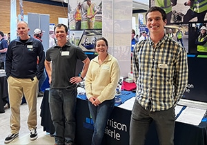 Three employee-owners pose at a career fair. 