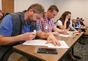 Two men and one woman looks down at papers on a shared desk.