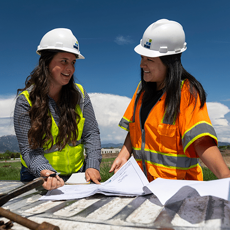 women wearing hard hats and safety vests in the outdoors with engineering plans morrison maierle engineering careers
